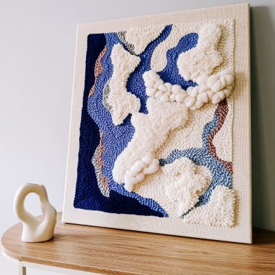 Abstrakcyjny obraz punch needle w biało-niebieskiej kolorystyce.