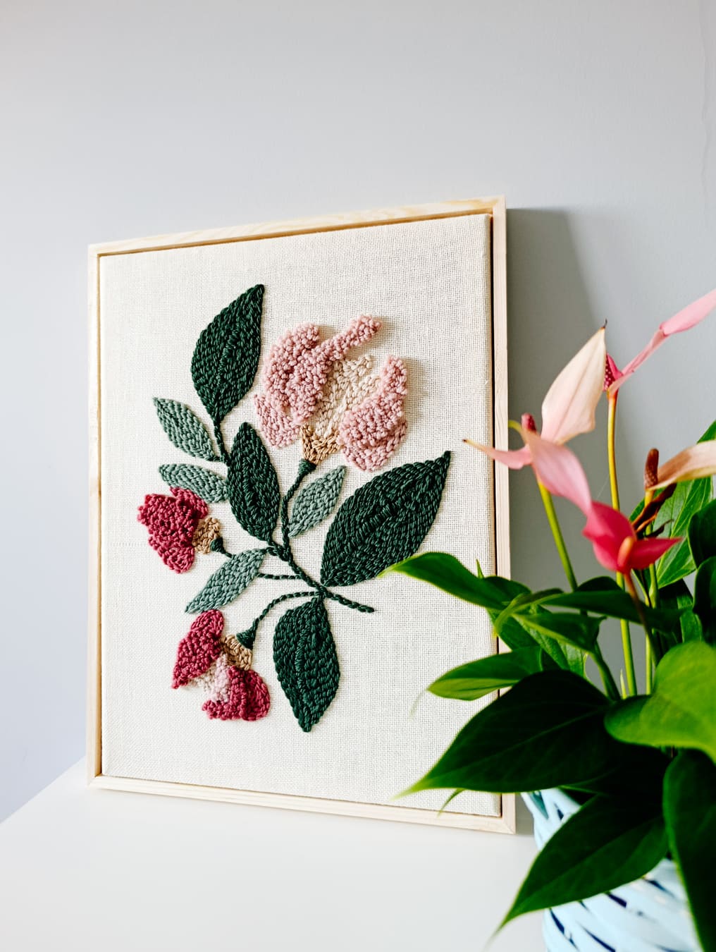 Ręcznie wykonany obraz techniką punch needle w odcieniach różu i zieleni oprawiony w wąską drewnianą ramkę. Dekoracja ścienna o kwiatowym wzorze, idealna do nowoczesnych i przytulnych wnętrz.