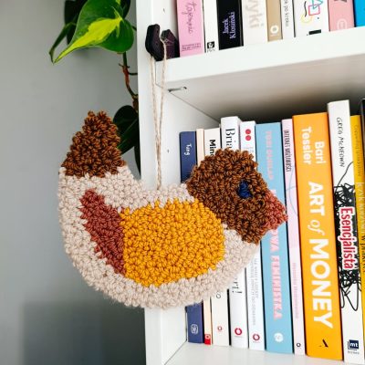 Zawieszka ścienna z wełnianych pętelek w kształcie ptaszka.