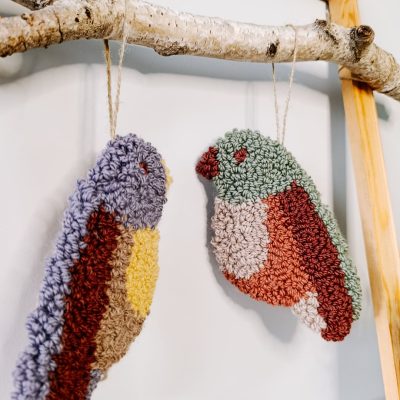 Zawieszka na ścianę z wełnianych pętelek w kształcie ptaszka.