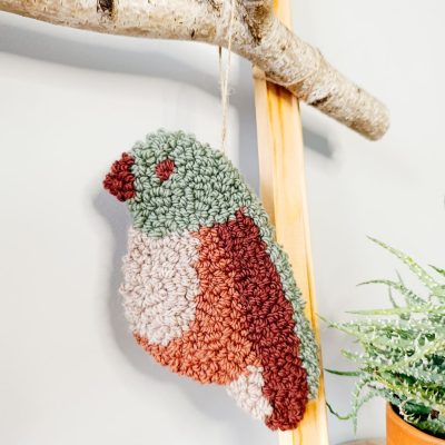 Zawieszka na ścianę z wełnianych pętelek w kształcie ptaszka.