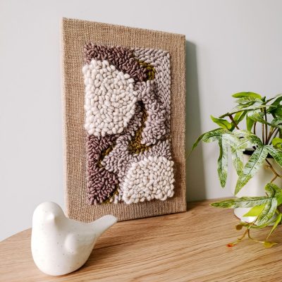 Obrazek wełniany z abstrakcyjnym motywem w kolorach ziemi.
