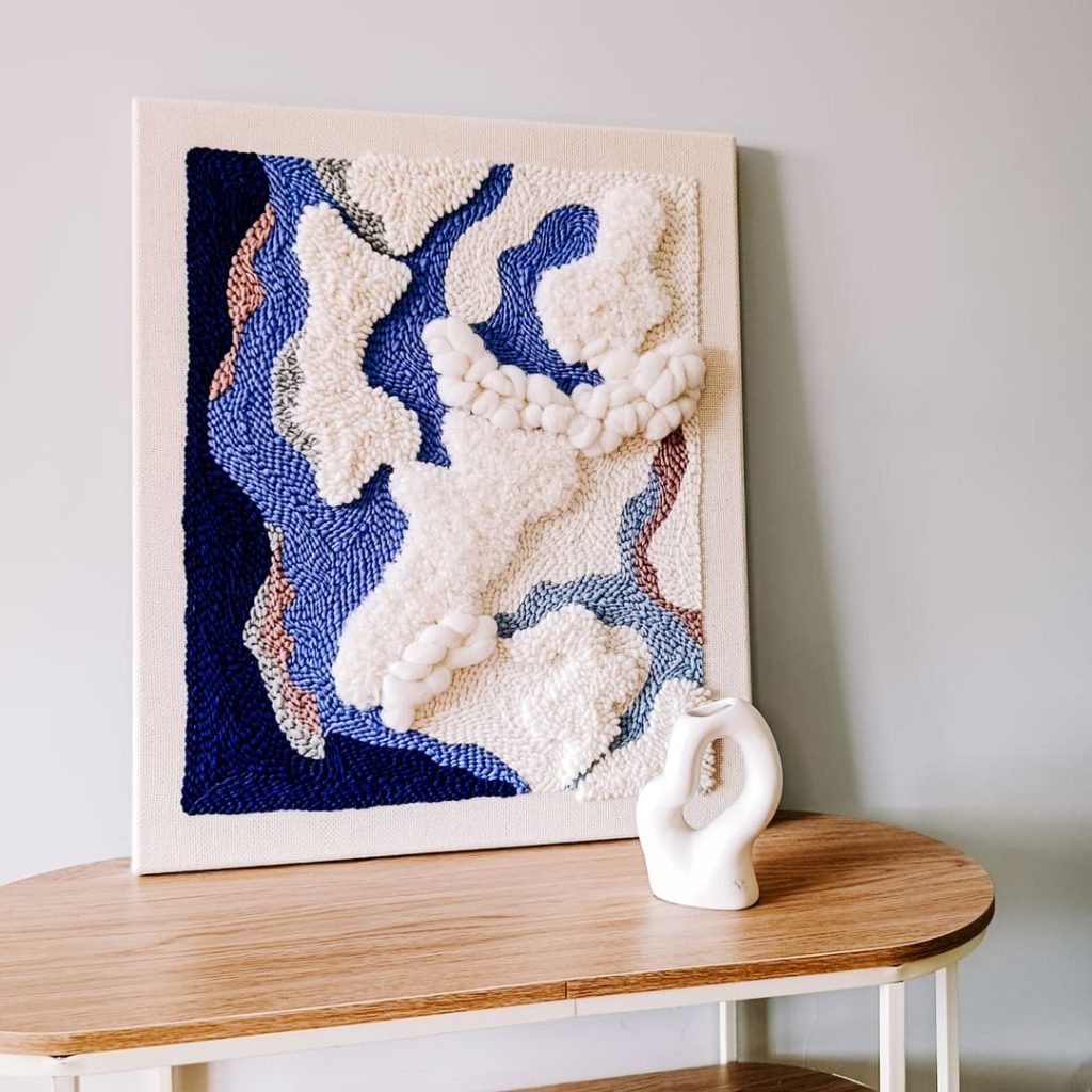 Obraz punch needle  w kolorach bieli i niebieskiego.